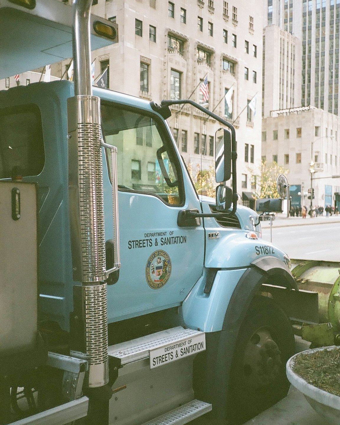 Un camion della nettezza urbana parcheggiato in una strada cittadina vicino a edifici alti.